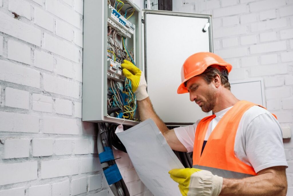 Electrician in gloves inspecting an electrical distribution box